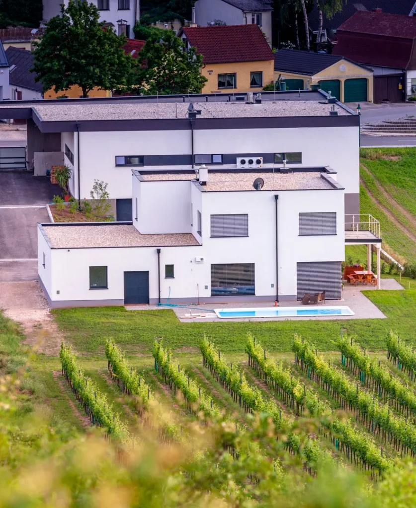 Weingut GILG mit modernem Gebäude und Pool, umgeben von gepflegten Weingärten